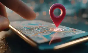 Palec wskazuje na mapę na ekranie telefonu, gdzie czerwony pin oznacza miejsce. Dowiedz się, jak udostępnić lokalizację.