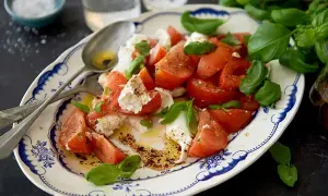 En härlig caprese sallad med saftiga tomater, krämig mozzarella och färsk basilika, ringlad med olivolja och balsamvinäger.