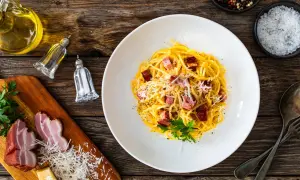 En tallrik krämig spaghetti carbonara med pancetta, toppad med parmesan och persilja. Perfekt vin till carbonara.