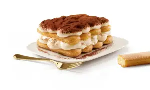 Un tiramisu généreux, fait avec 500g de mascarpone, est prêt à être dégusté. Une cuillère dorée et un biscuit à portée de main.