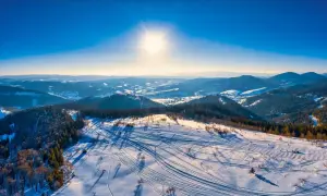 Sonniger Tag im Riesengebirge Skigebiet. Spuren im Schnee zeugen von einem lebhaften Tag auf den Pisten.