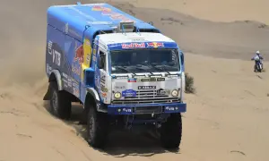 Camion Kamaz aux couleurs Red Bull, prêt à affronter le désert. La puissance camion Dakar se révèle dans ce paysage sablonneux.