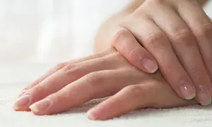 Delikatne dłonie z naturalnym, błyszczącym manicurem biologicznym. Paznokcie zadbane, z subtelnym połyskiem.