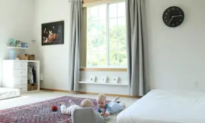 Two babies explore a room with a Montessori inspired feel, featuring a rug, toy basket, and artwork.