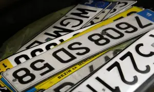 Stos tablic rejestracyjnych, w tym jedna z napisem "BEZIN SA MERCEDES". Widać fragmenty numerów, np. 8509L, 85DS, WGM.