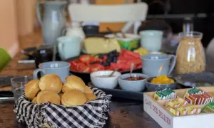 Frukostbuffé med korg full av nybakade scones över natten, frukt, ost och te.