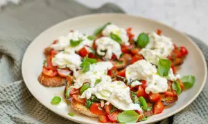 Bruschetta med burrata, färska tomater och basilika på en tallrik.