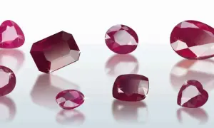 Glänzende Rubine, eine Form von Korund, in verschiedenen Schliffen und Größen, die auf einer reflektierenden Oberfläche liegen.