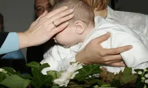 Rytuał chrztu: ręka matki błogosławi dziecko. Co zrobić że świeca po chrzcie? Zachowaj ją jako pamiątkę.