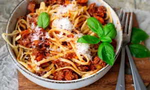 Eine Schüssel mit Linguine und einer herzhaften, **schnellen Bolognese**, garniert mit frischem Basilikum und Parmesan.