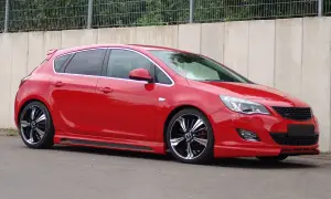 Czerwony Opel Astra J z przyciemnianymi szybami i efektownymi felgami. Widać jego światła pozycyjne.