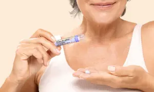 Une femme tient une perle de sérum contenant des peptides, prête à l'appliquer pour un soin anti-âge.