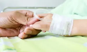 Dłoń rodzica trzyma dłoń dziecka w szpitalu, gdzie wystawiane jest zwolnienie na dziecko w szpitalu.