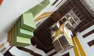 Widok z góry na wnętrze budynku z zielonymi, geometrycznymi formami i kasetonowym sufitem. Fotograf architektury uchwycił unikalną perspektywę.