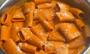 Rigatoni cremosi in salsa all'nduja, cosparsi di formaggio grattugiato. Un piatto invitante e saporito.