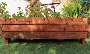 Mesa de cultivo de madera con flores y plantas verdes. Ideal para aprender cómo hacer una mesa de cultivo.