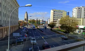 Widok na ruchliwą ulicę w Rzeszowie, z charakterystycznym budynkiem przypominającym żagiel w tle. W oddali widać **ogrody bernardyńskie rzeszów**.