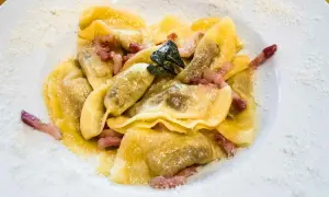 Deliziosi ravioli bresciani conditi con pancetta croccante e una foglia di salvia, spolverati di parmigiano.