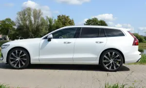 Białe Volvo T6 w wersji kombi stoi na tle zieleni i błękitnego nieba.