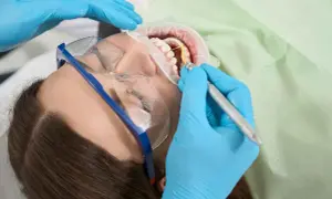 Dentysta wykonuje zabieg higienizacji zębów. Czas ten jest krótki, a efekt olśniewający.