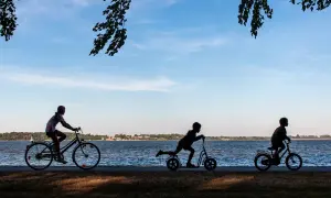 Dzieci na rowerach i hulajnogach przemierzają malownicze rowy trasy rowerowe nad jeziorem.