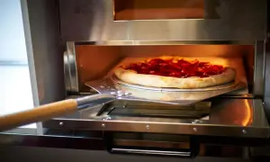 Pizza z pepperoni na łopacie wkładana do pieca.