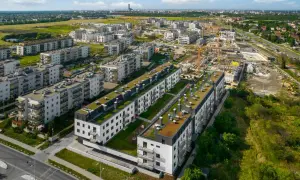 Nowe osiedle z zielonymi dachami, w tle budowa i miasto. Brak śladów powodzi.