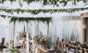 Udekorowane zielenią i kwiatami stoły tworzą magiczny styl boho na wesele. Delikatne tkaniny i girlandy dodają romantyzmu.