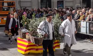 Hombres con trajes tradicionales desfilan en las fiestas Cuarte de Huerva, portando cestas con uvas y pan.