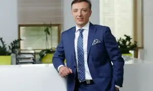 Mężczyzna w granatowym garniturze stoi w nowoczesnym biurze.