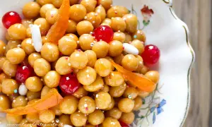 Struffoli ricetta napoletana: palline dorate glassate, decorate con canditi rossi, bianchi e scorzette d'arancia.