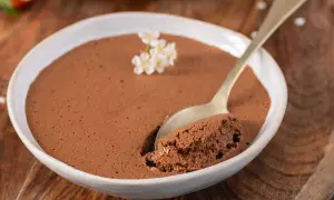 Une cuillère prend une bouchée d'une délicieuse mousse au chocolat, garnie de petites fleurs blanches.