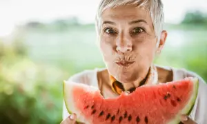 Glad kvinna med grått hår njuter av en saftig vattenmelon. Perfekt för ett uppfriskande vattenmelon recept.