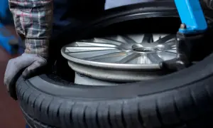 Mechanik w rękawiczce naprawia oponę samochodową na feldze.