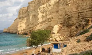 Piękna plaża Matala z turkusową wodą, piaszczystym brzegiem i skalistymi klifami. Mała tawerna zaprasza na odpoczynek.