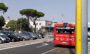 Czerwony autobus Ciampino Airlink, jadący do Rome Termini, stoi na parkingu obok innych samochodów.