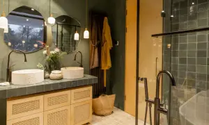 Bagno stile boho chic con doppio lavabo in pietra, mobili in legno e vimini, specchi irregolari e doccia con piastrelle verdi.