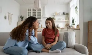 Mama rozmawia z nastolatką o zasadach w domu. Dziewczyna siedzi na kanapie, słuchając uważnie.