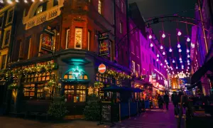 En livlig kväll i Soho, London, med The Blue Posts pub upplyst av julbelysning och neonskyltar.