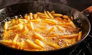 Frytki smażące się na głębokim oleju w czarnej patelni.