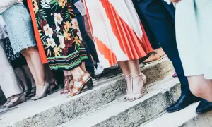 Gäste in festlicher Kleidung, die den **Dresscode Hochzeit** erfüllen, stehen auf einer Steintreppe. Bunte Kleider und elegante Schuhe.