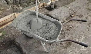 Taczka z betonem i łopatą, gotowa do wylania uziomu fundamentowego.