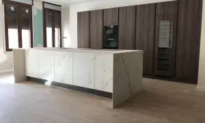 Cocinas modernas con barra central de mármol y gabinetes oscuros.