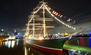 Großes Segelschiff mit Lichterketten und Flaggen im Hamburger Hafen bei Nacht, ein Highlight der museumsnacht hamburg.