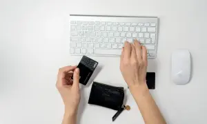 Ręce wpisują dane karty płatniczej na klawiaturze, przygotowując się do transakcji online. To pierwszy krok, jak zacząć sprzedawać w internecie.