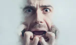 Przerażona twarz mężczyzny otoczona mgłą, jego oczy szeroko otwarte. Może to symbolizować lęk, niepokój, a nawet skutki uboczne leku, jak fluanxol.