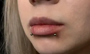 Zbliżenie na usta z przekłuciem typu cyber bites i biżuterią.