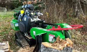 Grön stubbfräs med larvfötter redo att ta bort en stubbe i skogen.