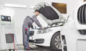 Mechanik sprawdza auto, by dowiedzieć się, ile kosztuje przegląd samochodu. Urządzenie diagnostyczne podłączone do silnika.