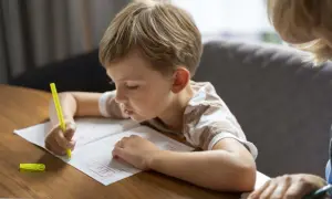 Niño concentrado practicando caligrafía en un cuaderno, un paso clave para como mejorar la letra de un niño.